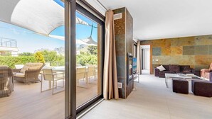 A spacious living area with a large sliding glass door leading to an outdoor patio, a flat-screen TV, and a stone accent wall. - Villa Cavall, Magnificent house 200 meters from the beach (Cala Sant Vicenç)