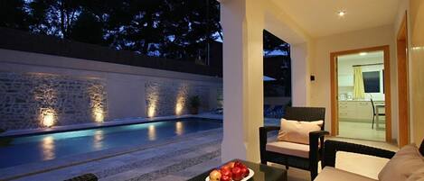 A poolside area with wicker furniture and a table with fruit.