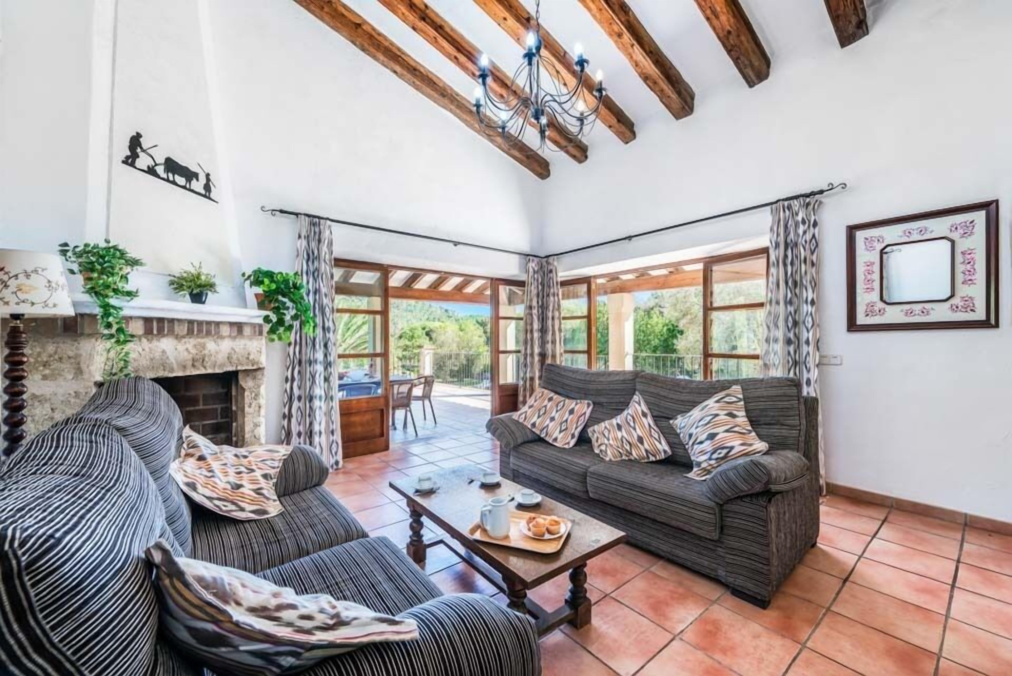 A spacious living room with a fireplace, two sofas, a coffee table, and large windows offering a view of the outdoors.