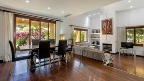 A spacious living area with a wooden floor, a dining table with chairs, a sofa, a television, and a fireplace. - Villa Formosa, One of the most loved properties. Impressive garden (Cala Sant Vicenç)