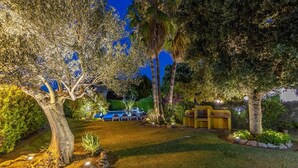 A well-lit garden with a swimming pool, stone pathway, and seating area. - Villa Formosa, One of the most loved properties. Impressive garden (Cala Sant Vicenç)