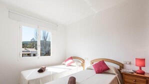 Een kamer met twee bedden, een raam, een houten nachtkastje en een rode lamp.