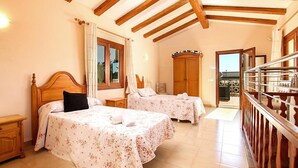 A hotel room with two beds, wooden ceiling beams, a balcony, and a view of the outside. - Villa Barraca, Peace and relax at 10m. walking to Puerto Pollensa (Port de Pollença)