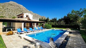 A swimming pool with lounge chairs, a stone pathway, and a mountain backdrop. - Villa Barraca, Peace and relax at 10m. walking to Puerto Pollensa (Port de Pollença)