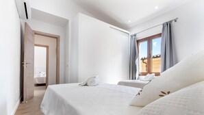 Hotellihuone, jossa on suuri sänky, avoimesta ovesta näkyvä kylpyhuone ja ikkuna, jossa on verhot.