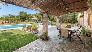 A covered outdoor area with a pool, lounge chairs, and a table with chairs. - Villa Butxaco, One of the most popular, and for good reason (Pollença)