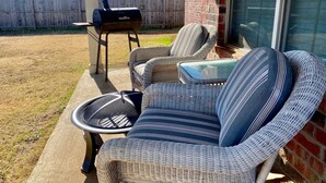 En terrasse med fletmøbler, grill og en murstensvæg.