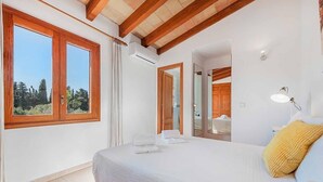 Ein Schlafzimmer mit einem großen Bett, einem Fenster mit Vorhängen, einer Klimaanlage und einer Holzbalkendecke.