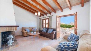 Ein geräumiges Wohnzimmer mit Kamin, zwei Sofas, einem Couchtisch und Blick ins Freie.