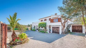 Ein modernes Haus mit Kiesweg, Holztor und einem Garten mit Pflanzen und Blumen.