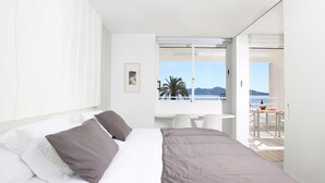 A modern hotel room with a bed, a desk, and a balcony with a view of the sea. - Sivella Apartament, Front-line studio located in Puerto Pollensa (Port de Pollença)