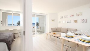 A modern hotel room with a balcony, a dining area, and a living space. - Sivella Apartament, Front-line studio located in Puerto Pollensa (Port de Pollença)