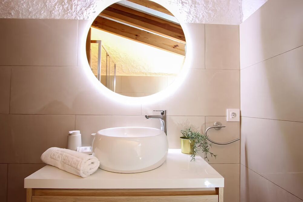 A bathroom with a round mirror, a white sink, and a towel on the counter.