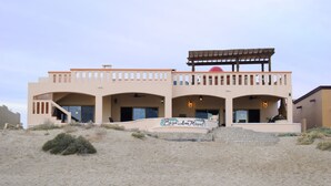 A two-story building with a flat roof, a covered patio, and a sign that reads "Casa de la Luna Miguel." - Casa San Miguel Beachfront House (Puerto Peñasco)