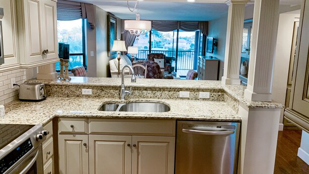 A kitchen with a stainless steel dishwasher, double sink, and built-in oven. - Vanderbilt Beach Access and on the intercostal! (Naples)
