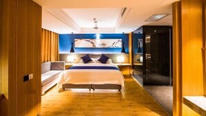 A modern hotel room with a large bed, a sofa, a desk, and a mirror. - Raspberry Boutique Hotel (Lanzhou)