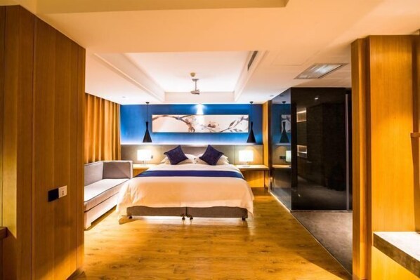 A modern hotel room with a large bed, a sofa, a desk, and a mirror. - Raspberry Boutique Hotel (Lanzhou)