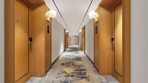A hotel hallway with wooden doors, recessed lighting, and a patterned carpet. - Raspberry Boutique Hotel (Lanzhou)