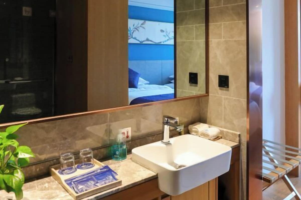 A modern bathroom with a large mirror, a white sink, and a towel rack.