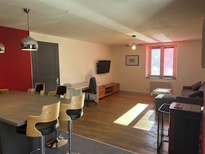 A modern living space with a dining area, a seating area, and a television.