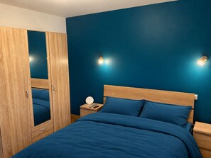 Ein Schlafzimmer mit einem Bett, einem Holzschrank, Nachttischen und Wandleuchten.