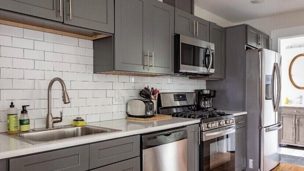 A modern kitchen with grey cabinets, stainless steel appliances, and a white tiled backsplash. - The Studio at Cleveland Park 2 bedroom 2 bathroom Near Lower Broadway (Nashville)