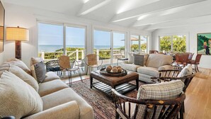 A spacious living area with a view of the ocean, furnished with a sofa, chairs, and a coffee table.