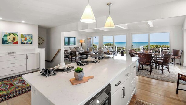 A spacious kitchen with a large island, dining area with chairs, and a view of the ocean.
