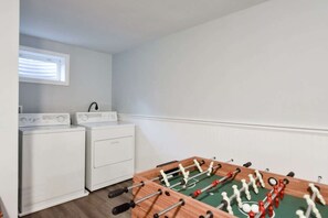 A laundry room with a washing machine, dryer, and a foosball table.