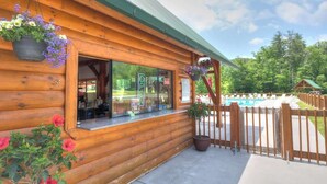 Une cabane en bois avec une porte en verre, un espace piscine et une clôture en bois.