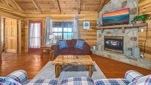 Un intérieur de chalet chaleureux avec une cheminée en pierre, un plafond en bois et des meubles à motifs écossais.