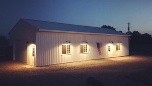 A single-story building with a gabled roof, a flagpole with an American flag, and exterior lighting.