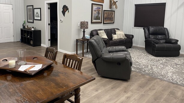 A spacious living room with a wooden dining table, leather sofas, and a black recliner.