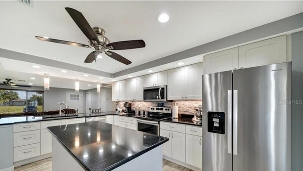 A modern kitchen with a central island, stainless steel appliances, and a ceiling fan. - Casa Florida, Pet-friendly, Child-friendly  (Port Charlotte)