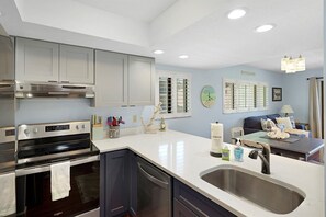 A modern kitchen with stainless steel appliances, a built-in oven, a dishwasher, and a large sink.