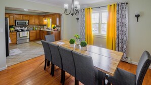 A dining area with a wooden table, grey upholstered chairs, and a chandelier. - "Modern 6BR Pocono Lake View Home Near Attractions W Balcony” (Covington Township)
