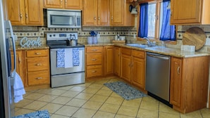 A kitchen with wooden cabinets, a stainless steel stove, a microwave, and a dishwasher. - "Modern 6BR Pocono Lake View Home Near Attractions W Balcony” (Covington Township)