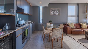 A modern kitchen with grey cabinets, a dining area with wicker chairs, and a leather sofa. - Umhlanga Arch - Ocean Views, Queen Size Bed, Free Wifi (Umhlanga)