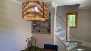 Un comedor con una mesa de madera, sillas y una lámpara colgante.
