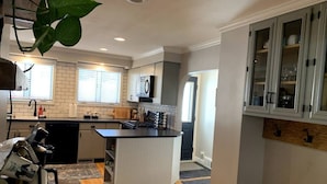 Una cocina moderna con una isla central, armarios blancos y un amplio ventanal que aporta luz natural.