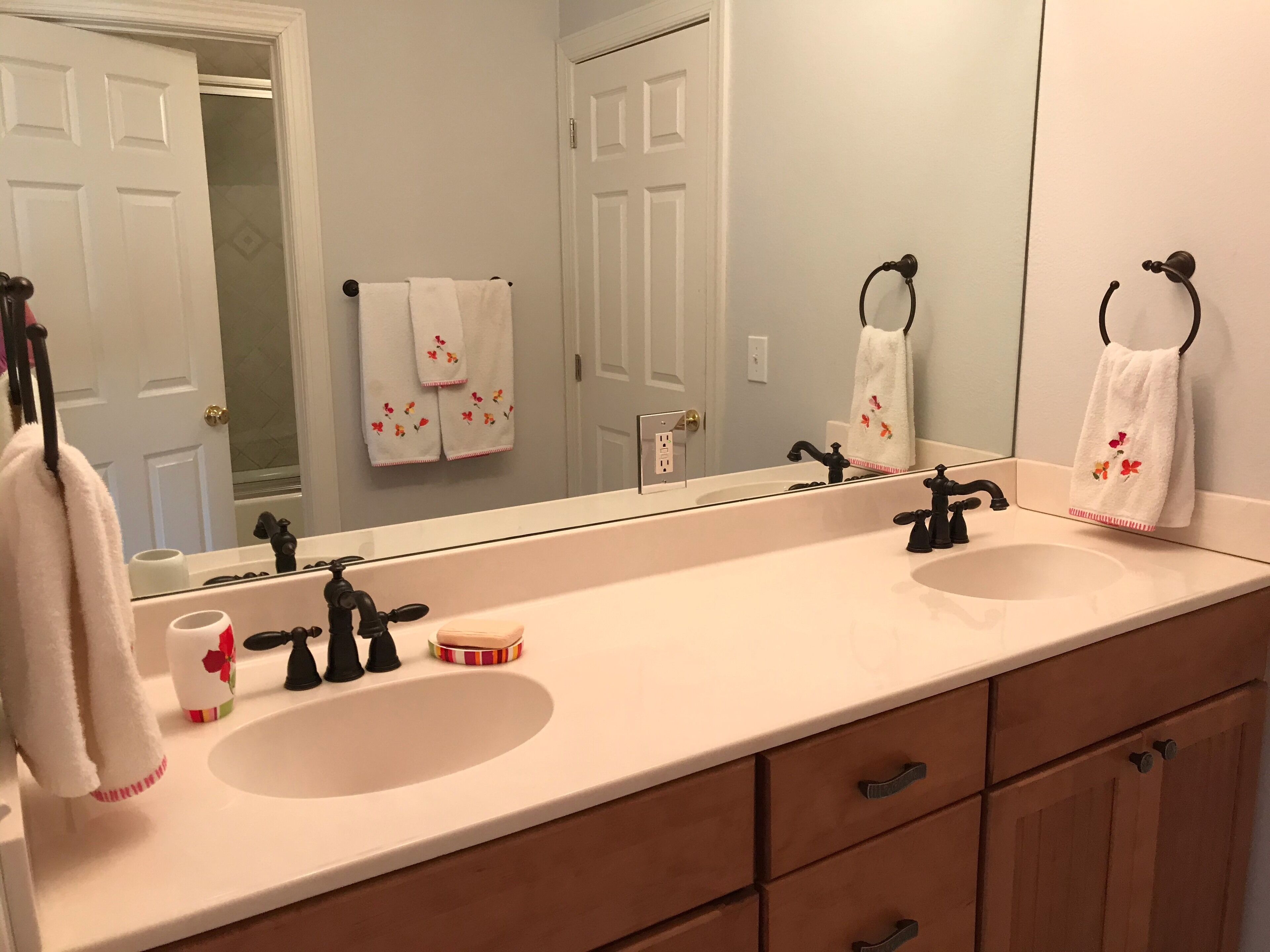 A bathroom with two sinks, a mirror, and a towel rack.