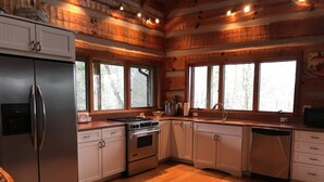 Una cocina moderna con paredes de madera, electrodomésticos de acero inoxidable y ventanas amplias.