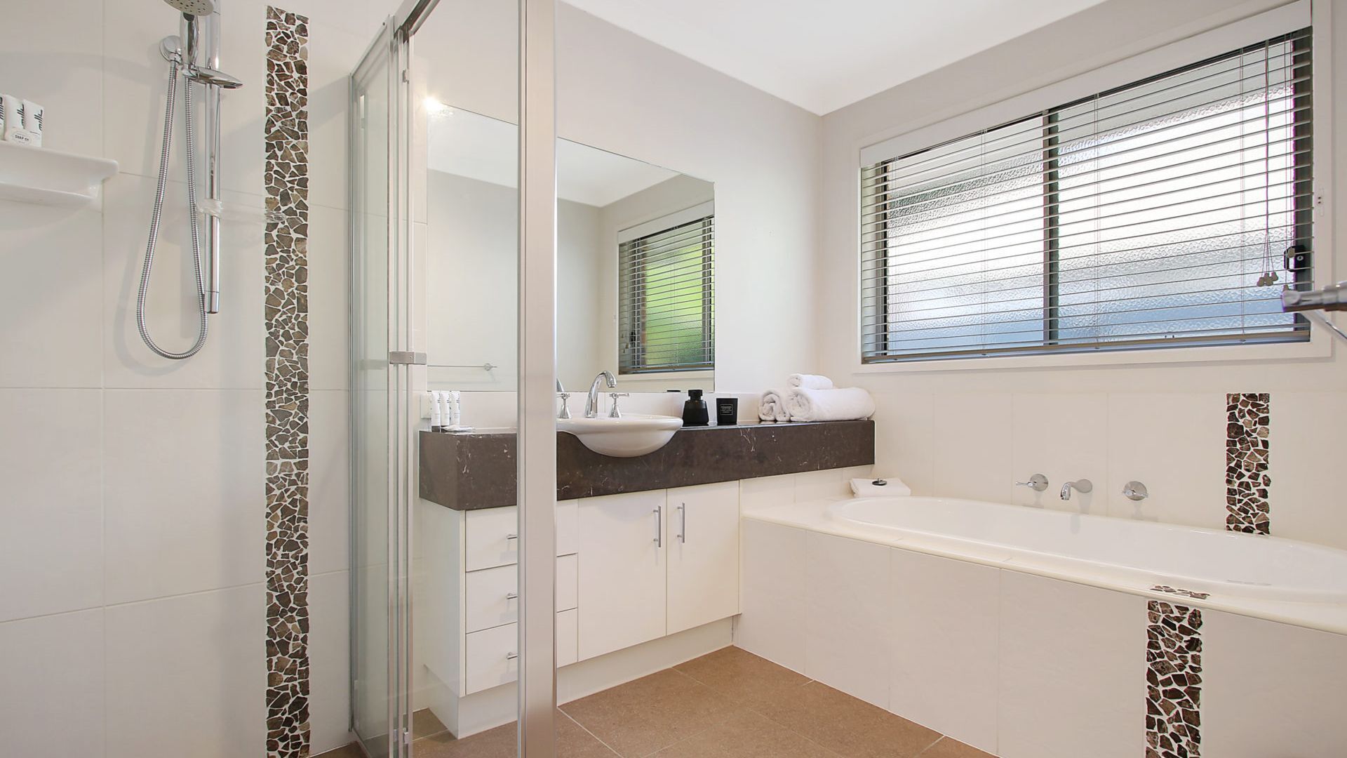 A modern bathroom with a glass shower enclosure, a large bathtub, and a vanity with a mirror.