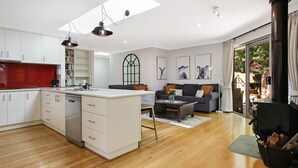 A modern kitchen with white cabinets, a central island, and pendant lighting. - Brighter Times - A private Haven, a place of calm. (BRIGHT)
