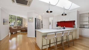 A modern kitchen with a central island, bar stools, and a red backsplash.