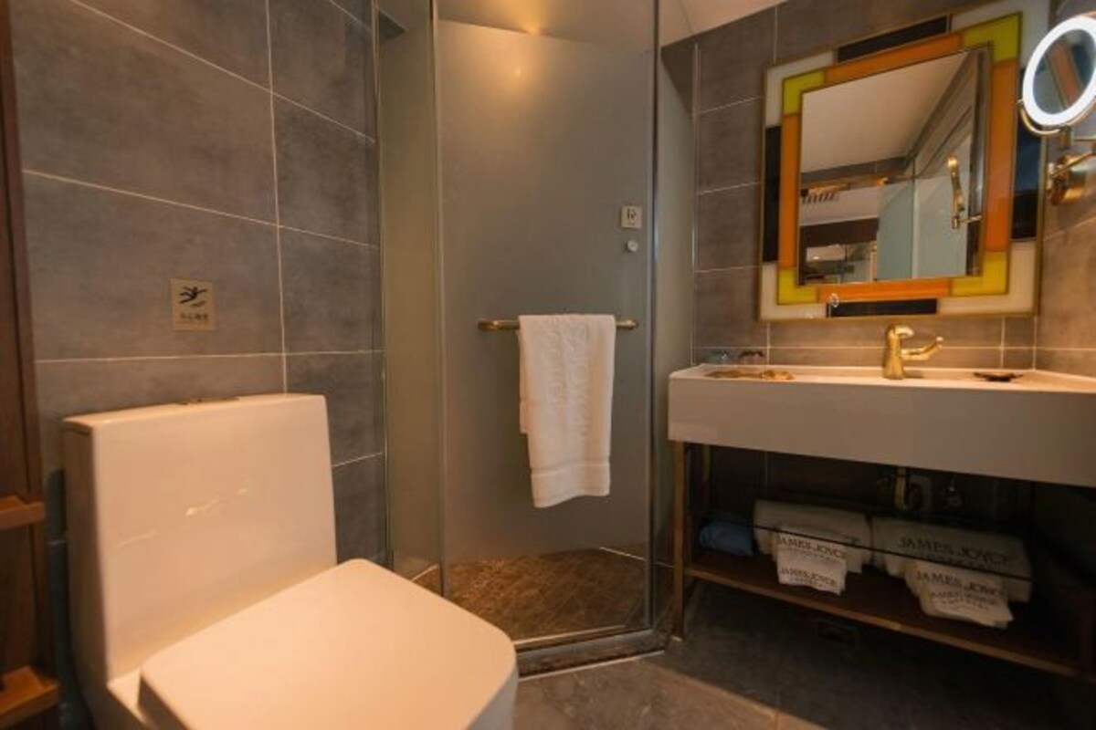 A bathroom with a toilet, a shower, and a sink with a mirror.