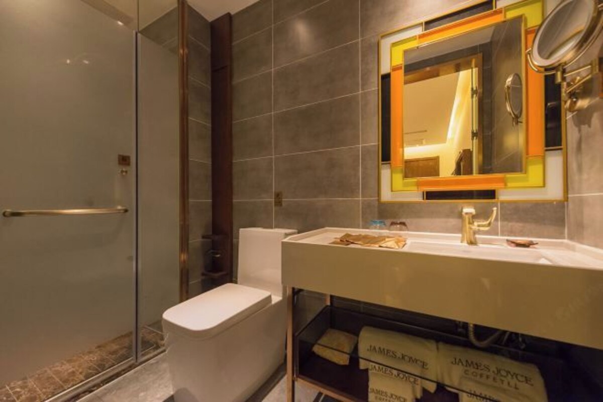 A modern bathroom with a glass shower enclosure, a white toilet, and a vanity with a mirror.