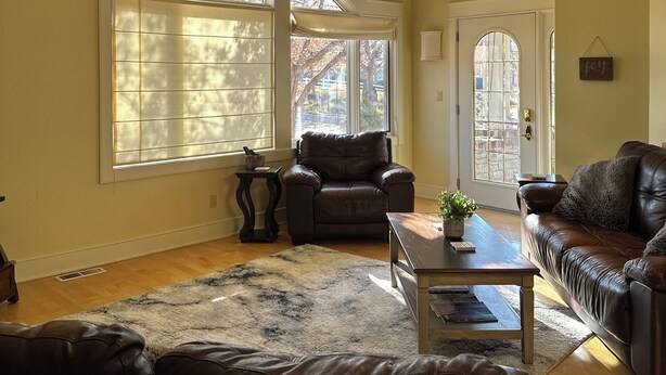 A spacious living room with a high ceiling, large windows, and a fireplace.