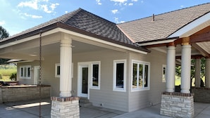 A house with a covered porch, stone pillars, and a tiled roof.