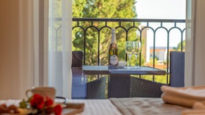 Varanda com mesa posta para dois, com uma garrafa de vinho e um copo.